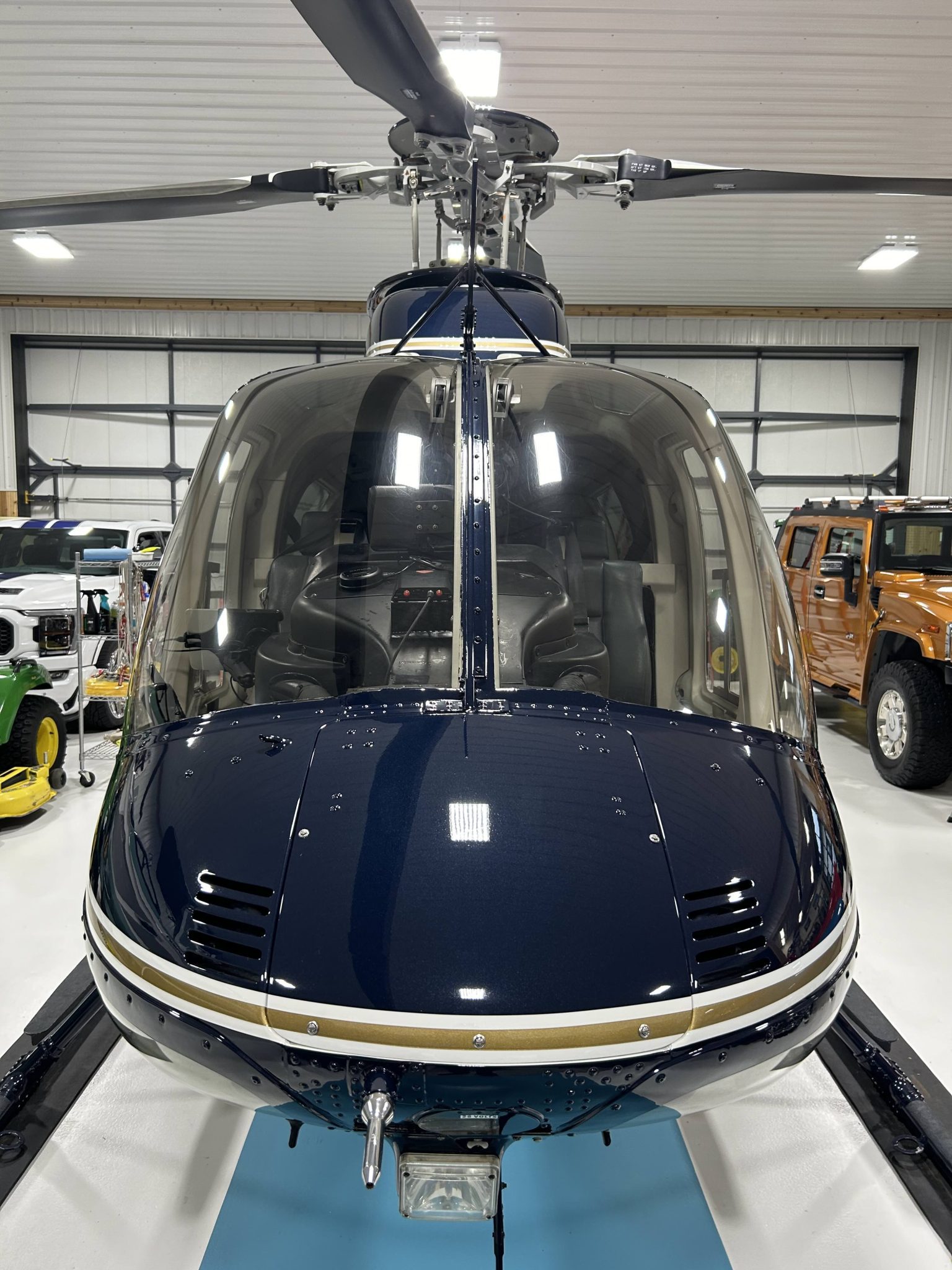 Cockpit view of a blue and yellow helicopter that is sitting in the Flawless Finishes auto detailing shop after being cleaned.